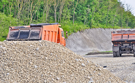 A pile of rock and gravel at a landfill with dump truck.