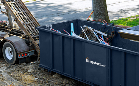 Blue Dumpsters.com dumpster filled with scrap metal being loaded on a truck.