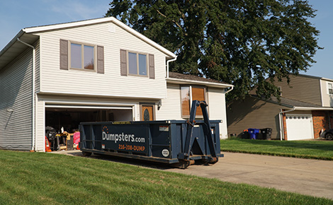 Dumpsters.com roll off dumpster in residential driveway by house with old tile.