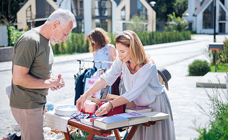 A man browsing a yard sale table with books.