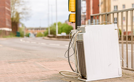 An old mattress and other trash on the curb.