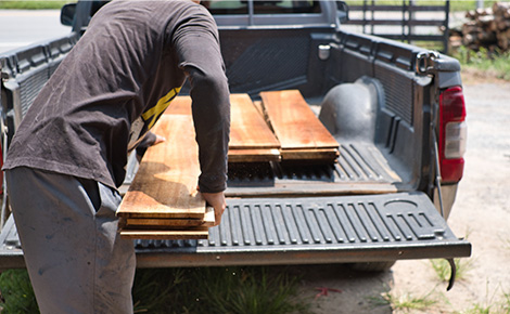 Homeowner loading lumber in truck bed to be sold.