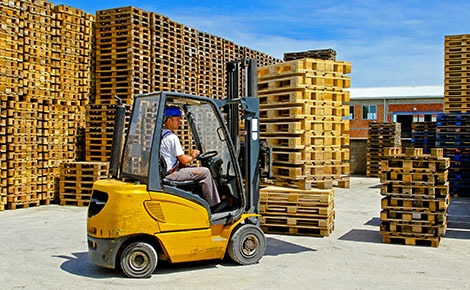 A forklift moving wood pallets that are ready to be processed.