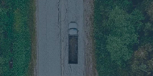 Dump truck driving along a wooded roadway.