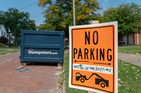 No Parking Sign in Front of a Blue Dumpster