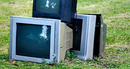 TVs stacked on a lawn.