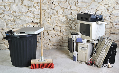 a pile of computer equipment next to a trash can