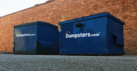 two front load dumpsters against a brick wall