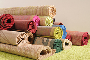 Rugs rolled up and piled on yellow carpet.