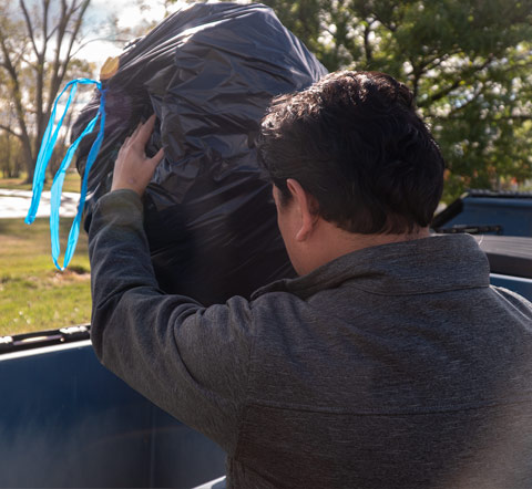 Man Putting Trash Bag in Front Load Dumpster