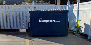 commercial dumpster next to a white fence