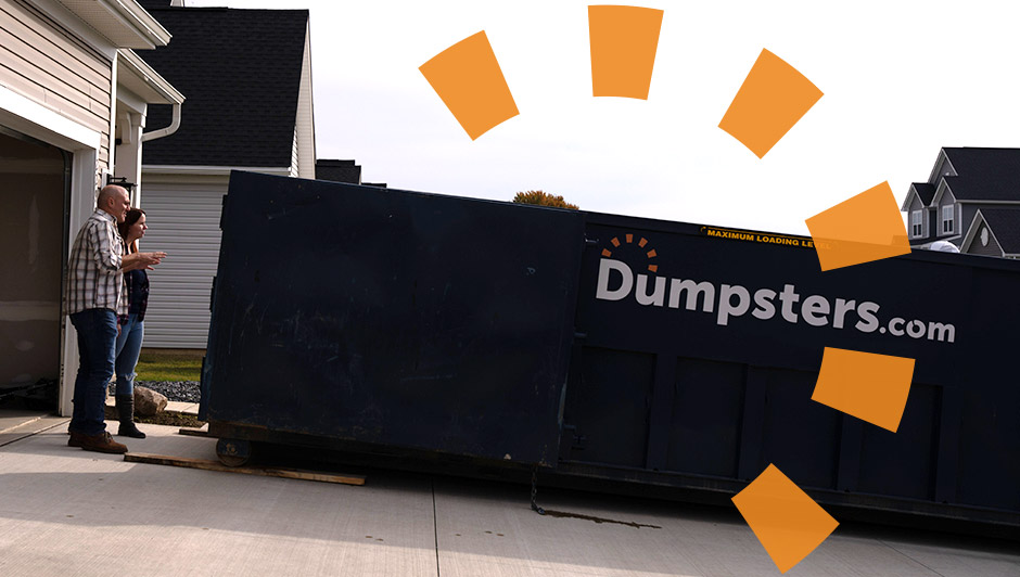 Man and woman standing next to empty blue dumpster on driveway