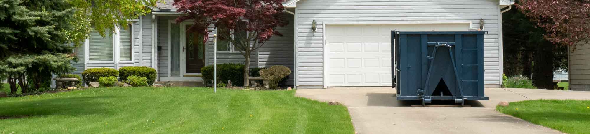 Roll Off Dumpster in a Residential Driveway In Front of a Garage