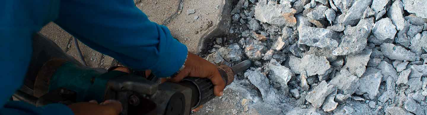 Worker Breaking Up Concrete for Disposal