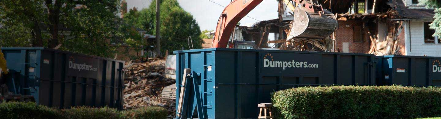 excavator loading a roll off bin with demolition debris