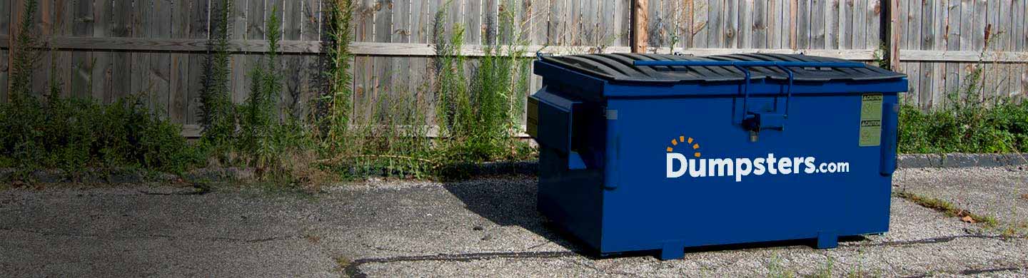 2 yard front load dumpster near a fence