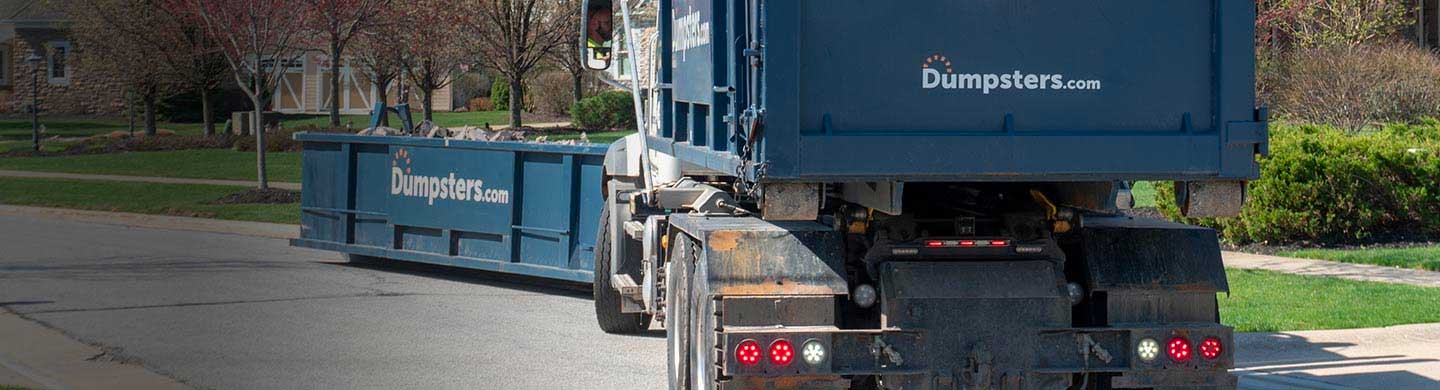 Dumpster Truck Driving Towards Overfilled Dumpster