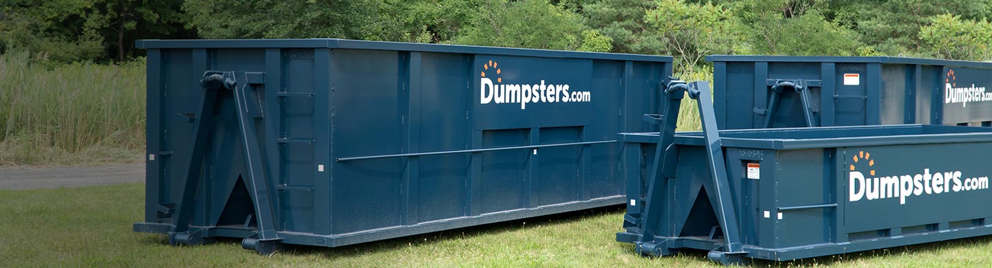 Several different dumpster sizes in grassy field