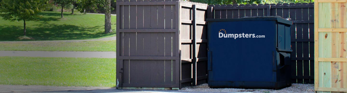 blue front load bin inside a dumpster enclosure in a park