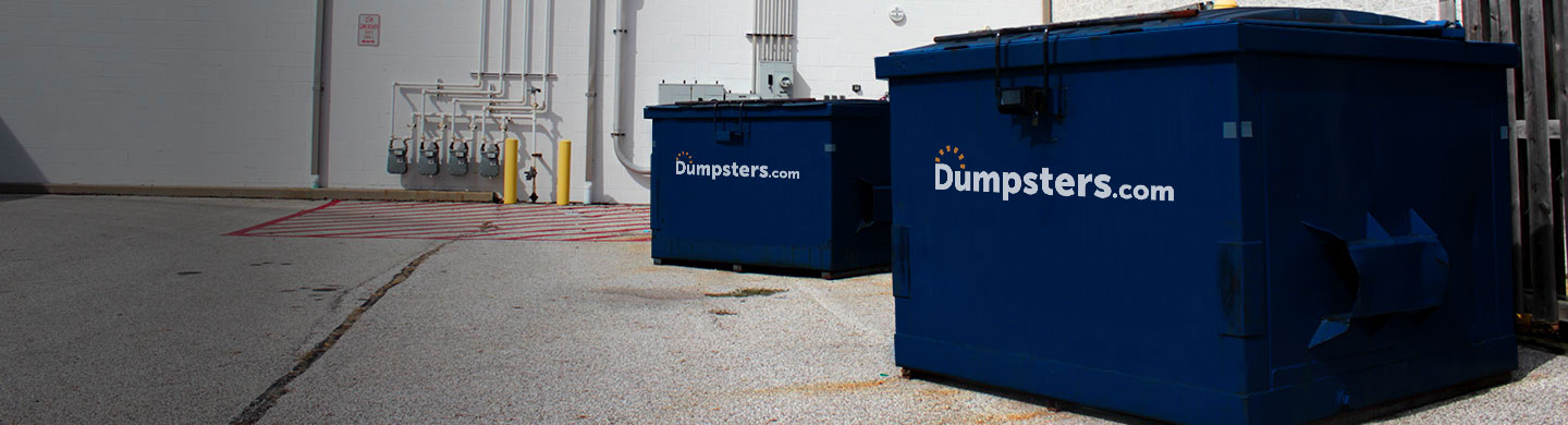 two blue front load bins outside of an industrial building