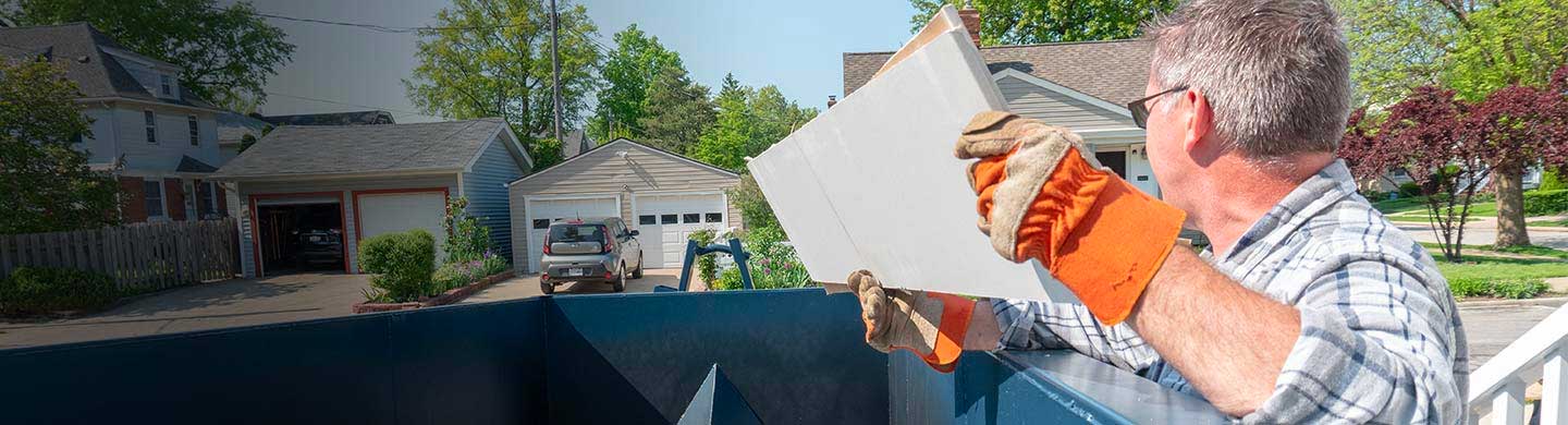 Man Throwing Debris Into a Roll Off Dumpster