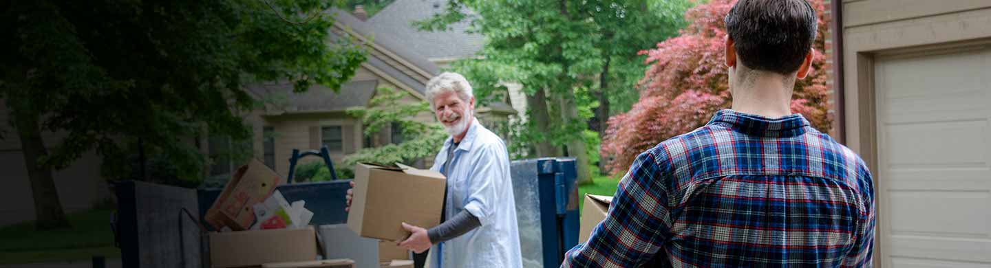 woman carrying carpet to roll off dumpster