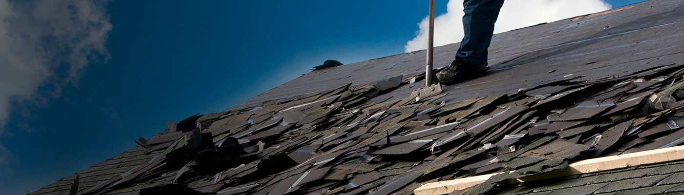 A Roofer Scrapes Asphalt Shingles from a Roof