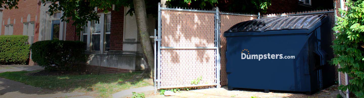 Front Load Dumpster in an Enclosure Outside of a School Building