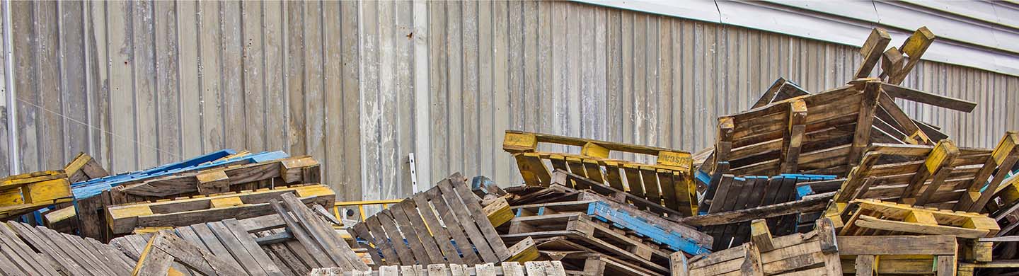 Stacks of pallets ready for disposal sitting outside of a warehouse.