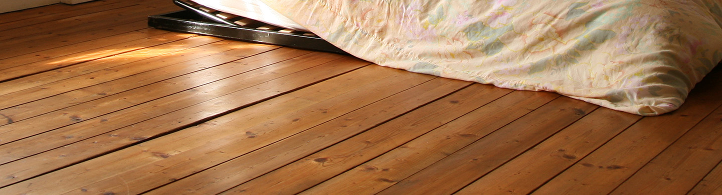 A mattress and bedding laying on a hardwood floor. 
