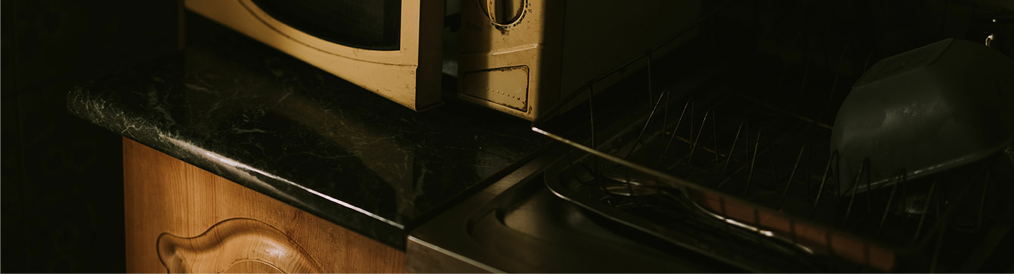 A close-up of an old microwave against a backsplash.