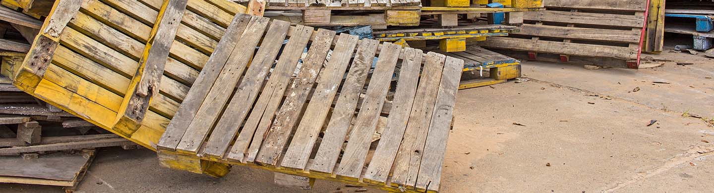 Used pallets thrown in a stack in storage.