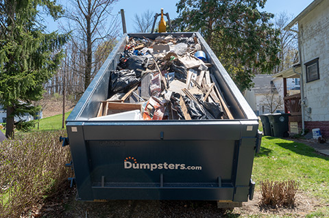 a dumpsters.com roll off dumpster filled with heavy debris