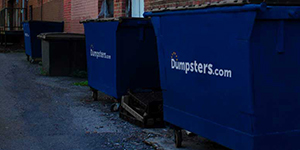 two commercial dumpsters in a back alley