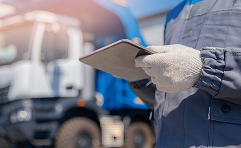 Junk removal service worker with gloves and clipboard next to truck.