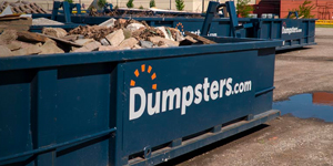 blue dumpster filled with junk on a construction site