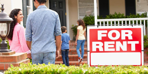 a family looking at a house with a for rent sign outside