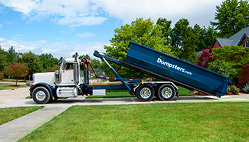 truck unloading roll off dumpster in a driveway