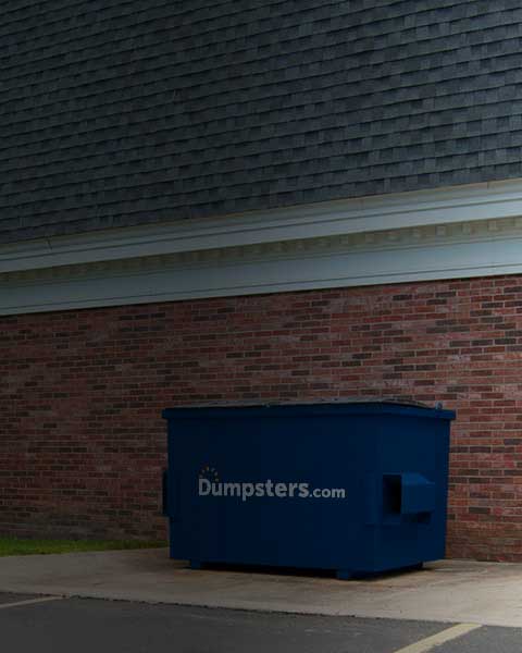 Dumpsters.com Commercial Dumpster Outside of Brick Building.