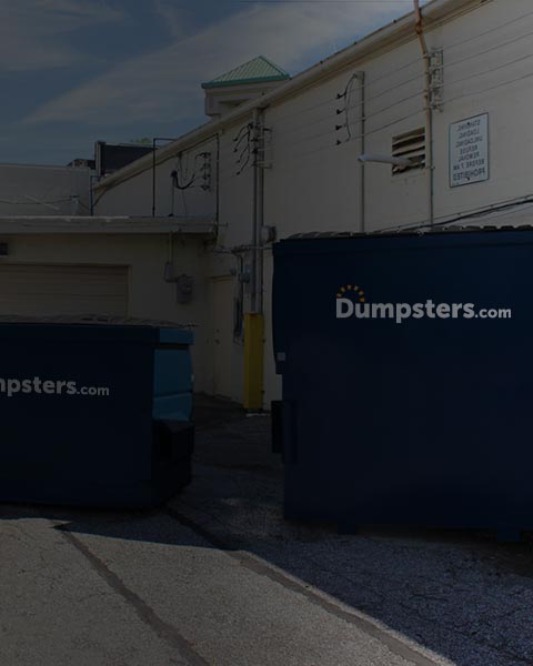 two permanent dumpsters of various sizes in a commercial parking lot