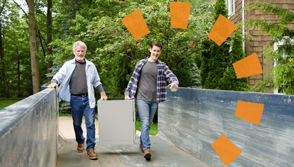 Two people loading a roll off dumpster with debris