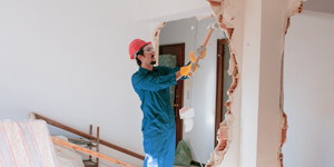 DIY homeowner demolishing a wall with a sledge hammer