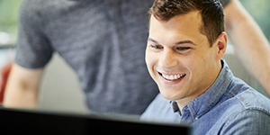 two dumpsters.com employees smiling at a computer