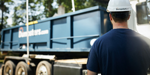 dumpsters.com truck driver facing away towards a dumpster