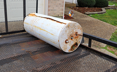 An old water heater sitting outside on a trailer.