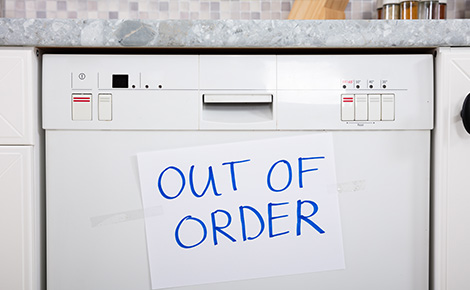 An broken dishwasher with an out of order sign on the front.