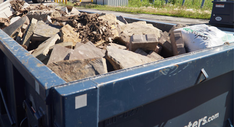 blue roll off dumpster full of heavy debris