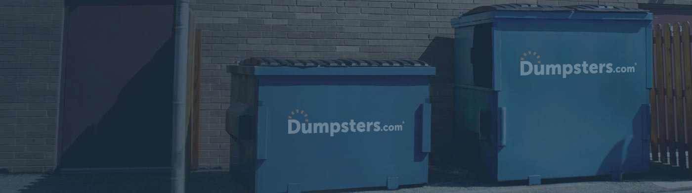 Two Dumpsters.com Front Load Dumpsters Behind a Building.