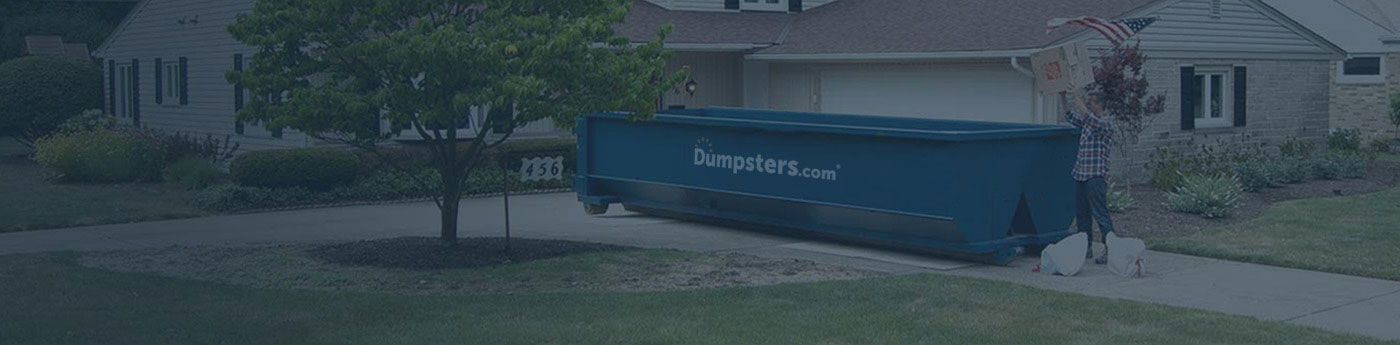 A Man Throwing a Box in a Dumpsters.com Roll Off Dumpster.