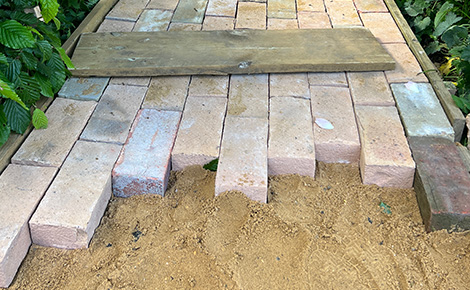 Reclaimed bricks being laid and reused for a walkway.